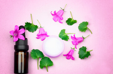 Organic cosmetics. A bottle with oil flowers and a jar of cream on a delicate lilac background.