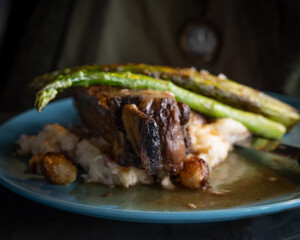 steak served with asparagus on a blue plate with dark background restaurant style gourmet recipe