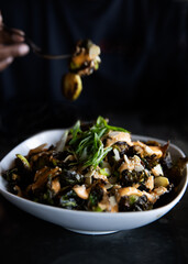 bowl of grilled veggies with a fork picking food up on dark background restaurant style gourmet recipe