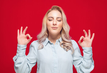 Concentration and enjoying. Young woman with closed eyes shows excellent sign with finger while...