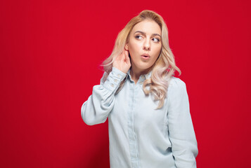 Gossip concept, woman holding hand near ear trying to listen something interesting, isolated on...