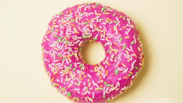Bright donut in a pink glaze with a multi-colored rainbow sprinkle on a pink background. Sweets and desserts. Minimalistic background with clean place for the inscription. Copy space. Soft focus.