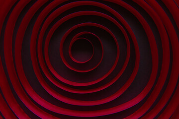 Maroon satin ribbon laid in circles in a spiral on a black background. An endless line, moving in a circle.