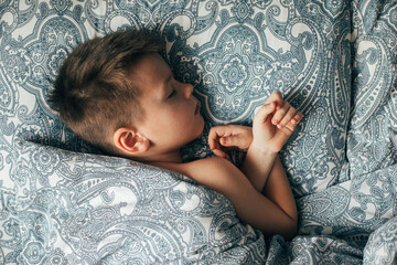 Adorable boy 6-7 years old sleeping in bed. Child having a good dreams.