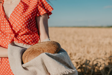 Homemade sourdough Bread Recipe. Homemade Artisan Bread in woman hands on wheat field background. Round bread in female hands