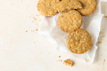 Healthy oatmeal or multigrain cookies with seeds and nuts on baking paper, light concrete background. Top view.