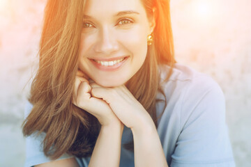 Beautiful woman smiles in the rays of the sunset light. High quality photo.
