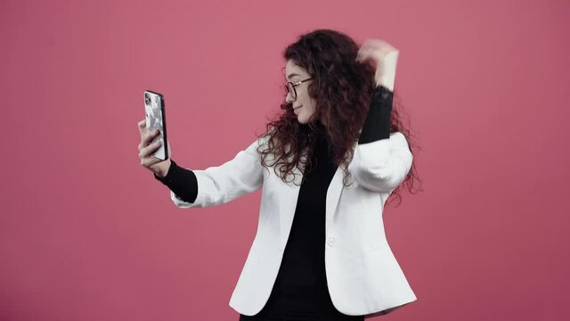 The young woman in love with curly hair, talking live with her boyfriend on the phone, arranges. Young hipster in white jacket and black shirt,