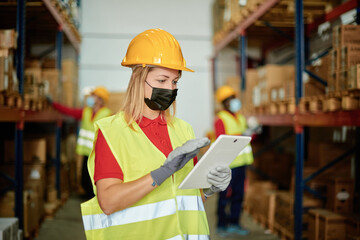 Portrait of a happy Caucasian female worker checking the order inside a warehouse while wearing a face mask - Face focus
