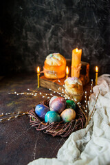 easter cake, candles, willow branches and painted eggs as a symbol of Easter on a dark background, wooden table