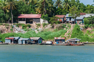 Blick vom Mekong auf den Uferbereich. Dieser ist gesäumt mit typischen Stelzenbauten, gebaut aus...
