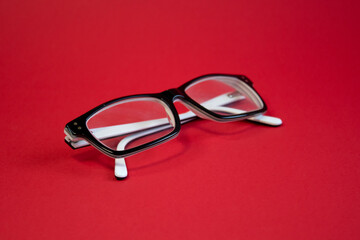 Stylish fashionable glasses in black and white frames on a bright red background close-up