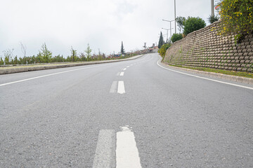 Fototapeta na wymiar Wide bright white street marking line along the modern wide straight empty asphalt highway to the horizon. Speed, safety, comfort travel and professional road construction concept.