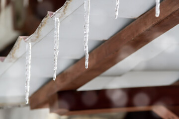 Icicles and a drop of melt water close-up. Snow melting. The beginning of the warm season