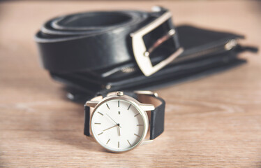 Set of men's accessories for the business with leather belt, wallet, watch and smoking pipe on a wooden background.
