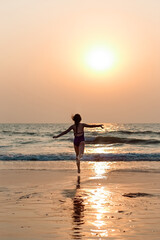 Fototapeta na wymiar happy preteen girl having fun running to the ocean, sea on a tropical beach at sunset. Concept of vacation, holidays, happiness, healthy lifestyle.