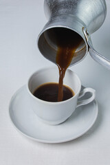 Coffee is poured into a coffee cup. Coffee is poured from a Turk. Espresso coffee