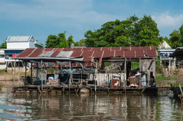 Blick vom Mekong auf den Uferbereich. Dieser ist gesäumt mit typischen Stelzenbauten, gebaut aus...