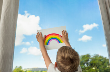 child holding up drawing of rainbow. Message of hope concept. 