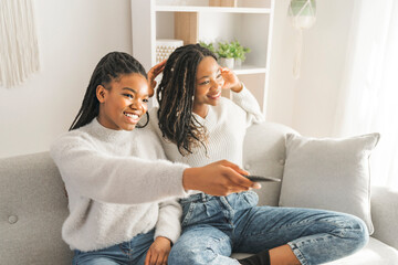 Mother and daughter sitting on sofa at home watching movie