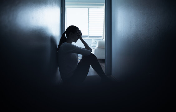 Sad lonely girl at home in a dark room. Divorce, loneliness, and stress concept. 
