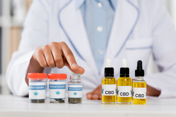 cropped view of doctor pointing with finger at bottles with legal cbd and medical cannabis