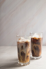 Cold sweet coffee with milk and ice on a light background. Copy space.