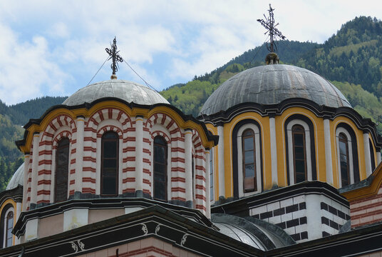 Brightly painted Church Domes at Rila Monastery, Bulgaria with forest in the background