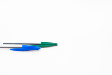 Blue and green ballpoint pens on a white background. Pens for drawing and writing.