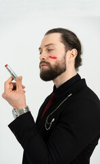Portrait photo of a man looking at red lipstick. A man is not afraid to be different people.