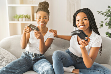 Mother and daughter sitting on sofa at home play video game together