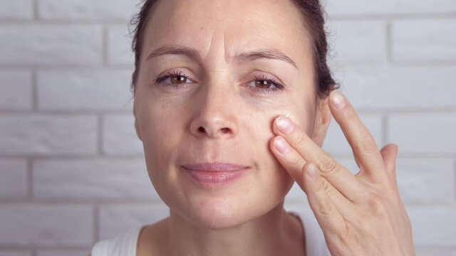 Facial skin care concept. A woman over forty smears her face with cream.