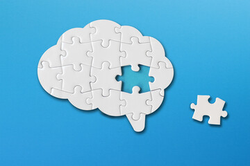 Brain shaped white jigsaw puzzle on blue background, a missing piece of the brain puzzle, mental health and problems with memory - obrazy, fototapety, plakaty