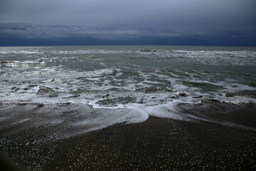 The ebb and flow of the waves on the shore in a windy cloudy day