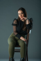Fototapeta na wymiar attractive brunette model sitting on a old chair posing and looking at camera on grey background