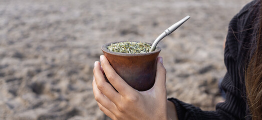 Selective focus of yerba mate in brown calabash gourd and with bombilla stick, tasty latin american...