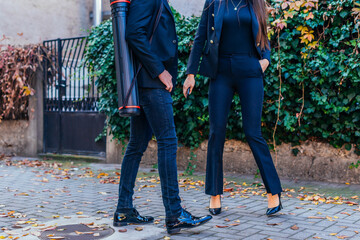 Close-up legs from two people in suits walking up the sidewalk in modern city.