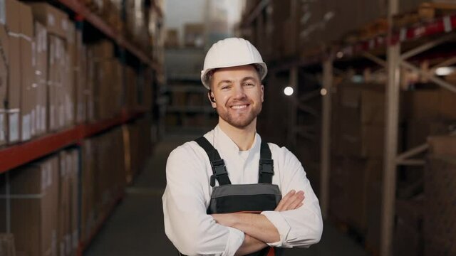 Close-up of a man in work uniform smiling at the camera on a background of shelves with boxes
