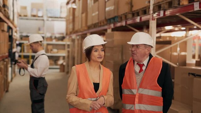 Solid elderly man communicates with the warehouse manager on the background of the worker