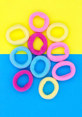 Multicolored little rubber bands for hair, on blue yellow paper background