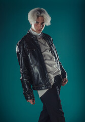 Male beauty concept. Portrait of fashionable young man with stylish haircut wearing trendy glasses and sweater, posing over gray background. Perfect hair & skin. Hipster style. Copy-space. Studio shot