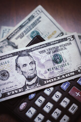 Five dollar bill with a calculator and twenty dollar bill background