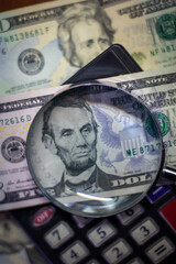 Five dollar bill with a magnifying glass and calculator