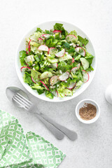 Salad bowl of fresh vegetables with radish, cucumber, romaine lettuce, bell pepper and greens. Healthy food