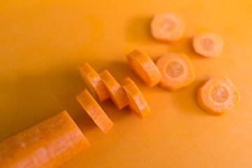 Fresh raw carrot slices isolated on an orange background, top view