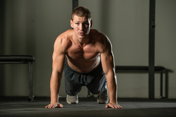 Fototapeta na wymiar Strong male athlete doing push-ups indoors. Close up perspective, healthy lifestyle, fatless body.