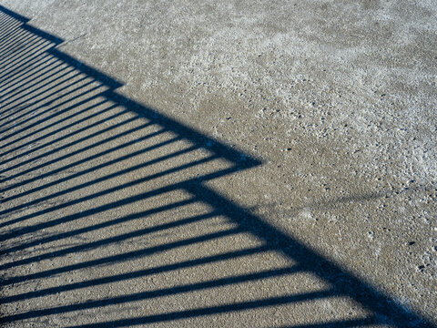perspective shadow of metal fence on pavement