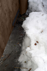 Under a wooden gate with a metal loop - ice, next to a snowdrift of loose spring snow with lacy shiny edges. Don't pass! Vertical.