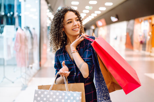 Young woman after shopping with shopping bags walks in the mall. Spring shoopping. Purchases, black friday, discounts, sale concept.