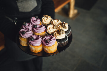 Waiter is serving a platter of yummy blueberry and chocolate cupcakes